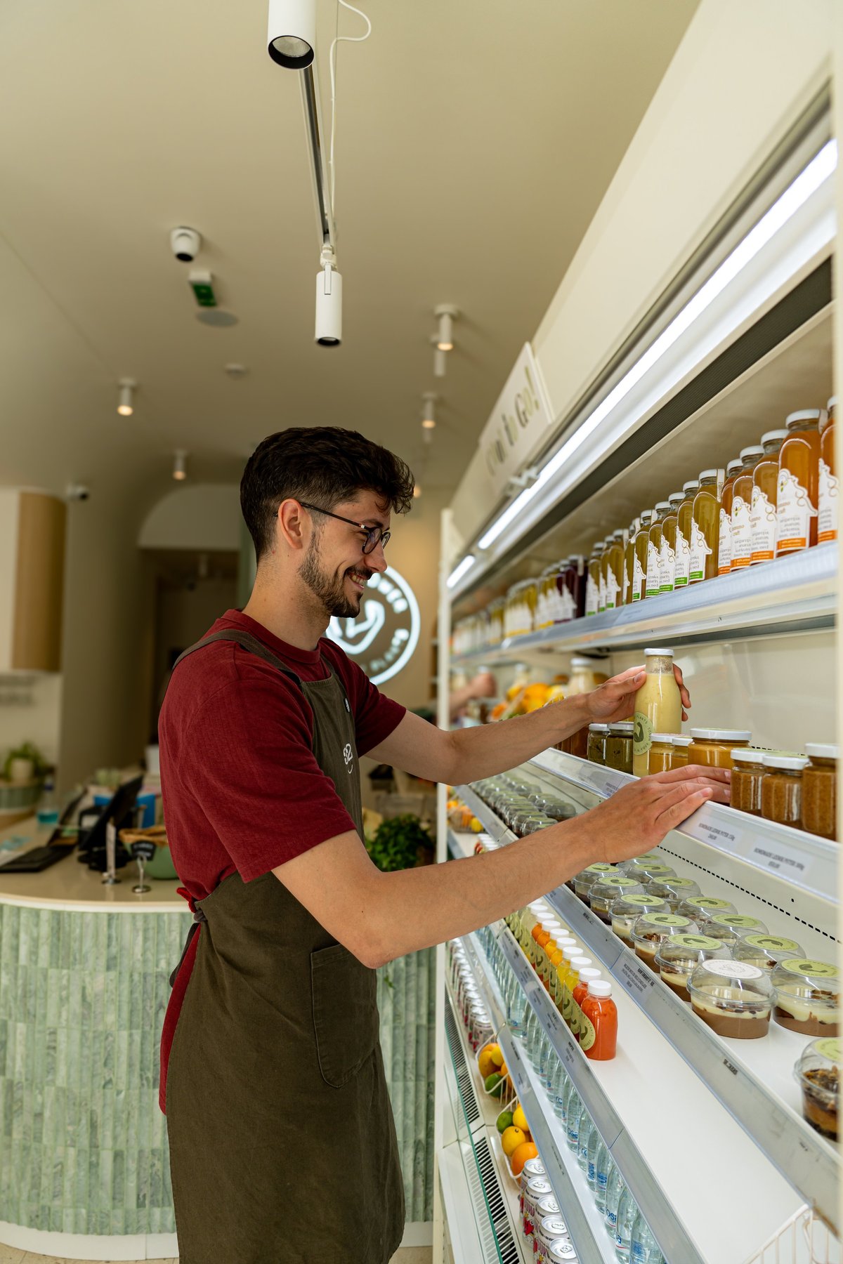 Young man arranging juice bottles in a modern health food store