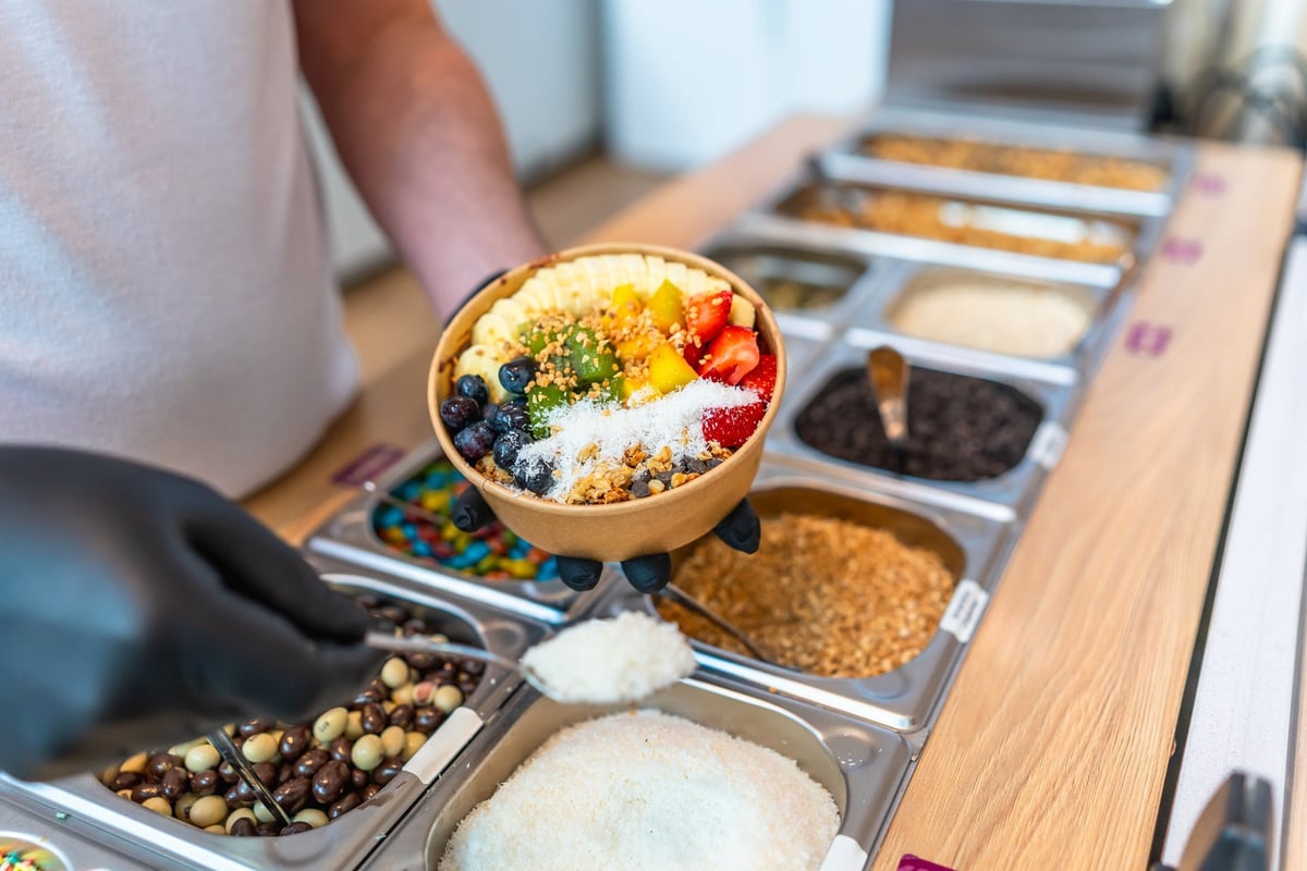 Person serving colorful acai bowl at cafe counter